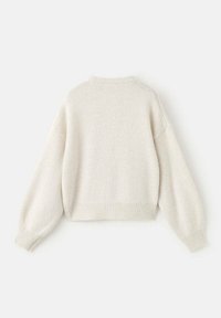 Krémový svetr s texturovaným pletením, oversize střihem, kleslými rameny a žebrovanými manžetami a lemem. Zadní pohled ukazuje jednoduchost designu.
