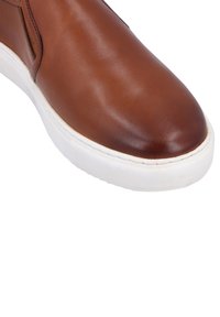 Braune Leder-Sneaker mit abgerundetem Zeh, elastischen seitlichen Einsätzen und einer weißen Gummisohle. Glatte Textur mit subtilem Glanz.