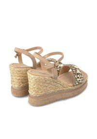 Sandalias de cuña con un talón de yute tejido natural, tiras de ante beige y adornadas con cristales transparentes en la parte delantera.
