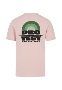 Světle růžové bavlněné tričko s černou grafikou s nápisem "PRO TEST" a zeleným půlkruhovým vzorem, s nápisem "SUN SEA SURF" pod tím.