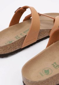 Brown leather sandals with two adjustable straps, cork footbed, and a black rubber outsole. Features embossed logo on the side.