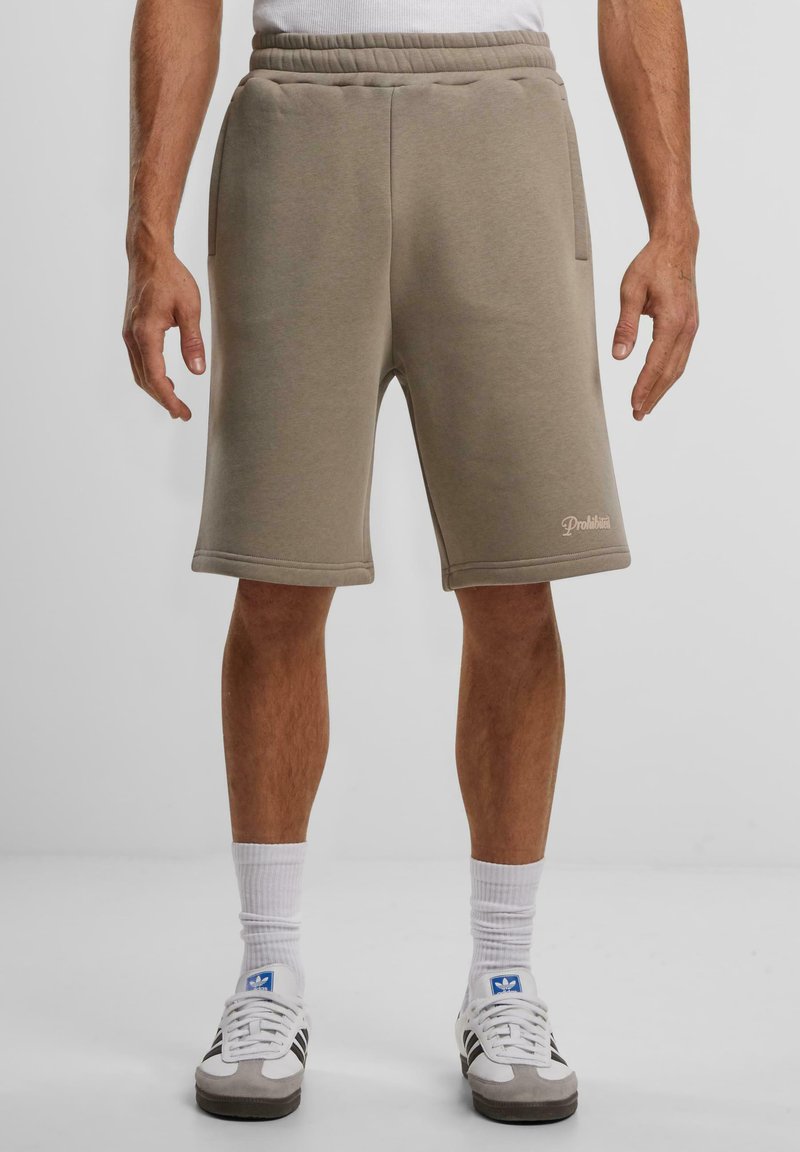 Beige sweatshorts laget av mykt stoff, med avslappet passform, sidelommer og en subtil logo-detalj på kanten.