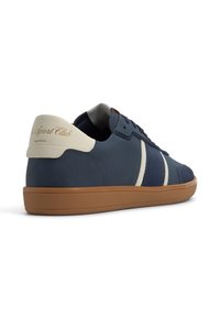 Baskets bleu marine en daim et cuir, avec des rayures crème, une semelle en caoutchouc beige et un logo sur le talon.