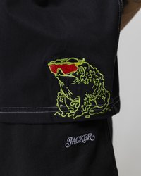 Black fabric shirt featuring a green embroidered frog with red sunglasses and the word "JACKER" in silver embroidery on the hem.