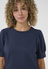 Navy blue cotton t-shirt with short puff sleeves, a round neckline, and a smooth texture, featuring a relaxed fit and simple design.