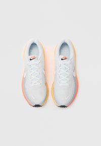 Jasnoniebieskie siateczkowe buty sportowe z białymi sznurowadłami; z pomarańczowymi i żółtymi akcentami na podeszwie oraz szarymi detalami po bokach.