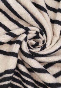 Tessuto lavorato a maglia di colore crema con righe orizzontali nere, morbida texture, arrotolato in una forma circolare, che mostra un contrasto di colore e un motivo distinti.