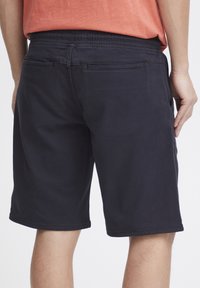 Marina blå shorts i bomull med elastisk midja och sidofickor. Har rena linjer och en avslappnad design utan utsmyckningar.