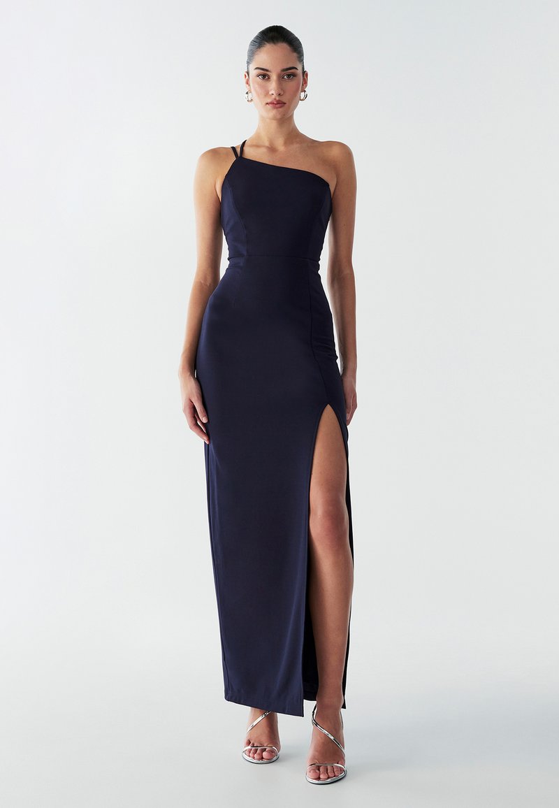 Tamsiai mėlyna, viena petneša satino suknelė su kojų aukščio skeltuku ir prigludusia forma. Pabrėžia kūno siluetą su minimaliais aksesuarais.