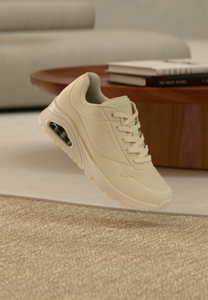 Beežid tossud võrgust pealiskihiga, paeltega suletavad ja perforatsiooniga detailid. Tald sisaldab nähtavat õhksuspatja.