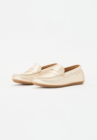 Goldene Lederloafers mit glatter Oberfläche, Mokassinstichen und einer flexiblen Gummisohle; Logo auf der Seite geprägt.