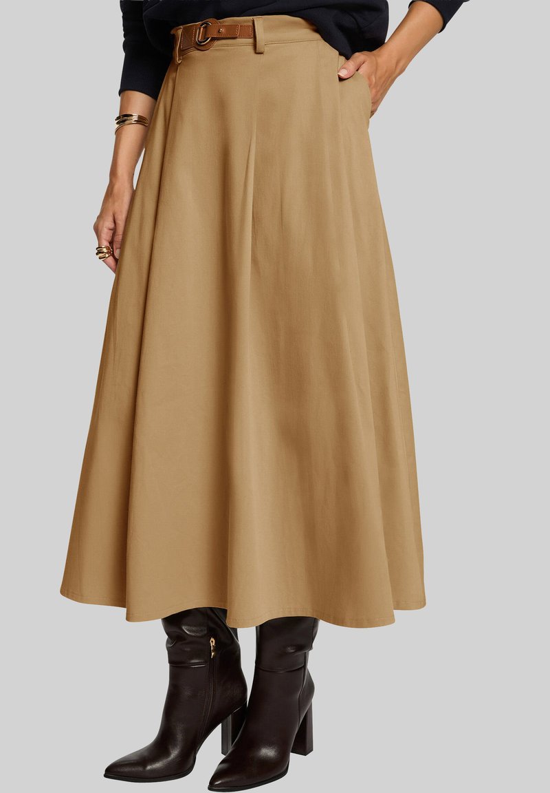 Une jupe midi beige plissée, dotée d'une ceinture tan, accompagnée de bottes en cuir marron montant jusqu'aux genoux, avec un bout pointu et un talon bloc.