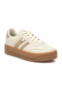 Zapatillas blancas con acentos beige, hechas de cuero suave, con tres detalles a rayas, cordones planos y una suela de goma texturizada.