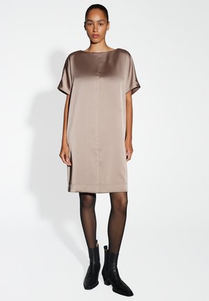 Satijnen taupe jurk met een boot-neklijn, korte mouwen en een eenvoudige silhoutte. Gemaakt met zwarte enkellaarsjes en sheer zwarte panty.