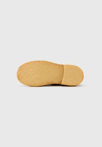 Καφέ καουτσούκ σόλα παπουτσιού με υφασμένη επιφάνεια, στρογγυλεμένο σχήμα και ελαφρύ τακούνι. Λείες άκρες και ελάχιστη ορατή ένδειξη μάρκας.