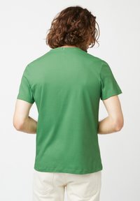 Groene katoenen t-shirt met korte mouwen, een ronde hals en een rechte zoom. Heeft een subtiele label aan de achterkant van de hals. Soepele textuur.