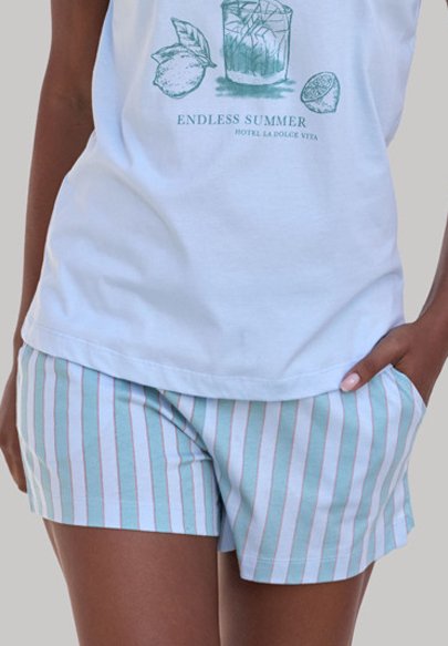 Top sin mangas azul claro con un estampado gráfico; combinado con pantalones cortos a rayas en azul claro y colores pastel, con cinturilla elástica y bolsillos.