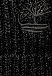 Czarna, dziana czapka z teksturowanym wzorem prążkowym oraz subtelnym haftowanym logo w kształcie drzewa. Miękki, ciepły materiał.