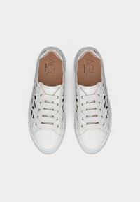 Ζευγάρι λευκών αθλητικών παπούτσια με κορδόνια, με κοψίματα στα πλάγια και ταμπά εσωτερικές σόλες με την επωνυμία "AGL", απεικονίζεται από πάνω σε λευκό φόντο.