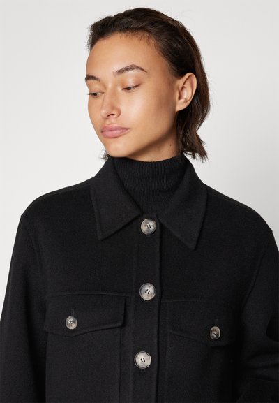Schwarze Wolljacke mit Kragen, versehen mit großen Knöpfen und zwei vorderen Taschen. Der Stoff hat eine glatte Textur und bietet Wärme.