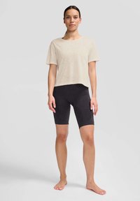 Lys beige kortærmet t-shirt med en afslappet pasform og tekstureret mønster, parret med mørke grå knælange cykelshorts.
