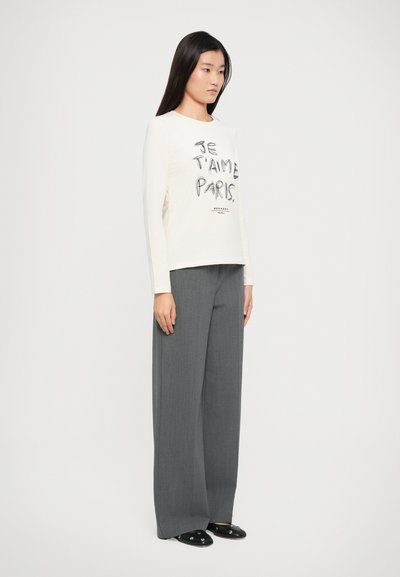 Lichtcrème langemouwen shirt met zwarte tekst "Je t'aime Paris" en brede grijze broeken. Gladde stof met een relaxte pasvorm en eenvoudig ontwerp.