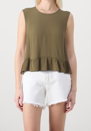 Olivengroen, mouwloos topje met een gestructureerde afwerking en een gerimpelde zoom. Gecombineerd met witte denimshorts met rafelige randen.