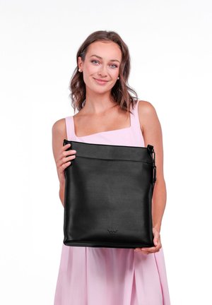 Černá kožená taška s horním zipovým uzávěrem, měkkou texturou a decentním logem dole. Taška má nastavitelné ucho.