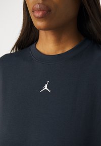 T-shirt bleu foncé en coton, arborant un logo Jumpman blanc sur la poitrine. Encolure ronde et manches courtes. Texture lisse.