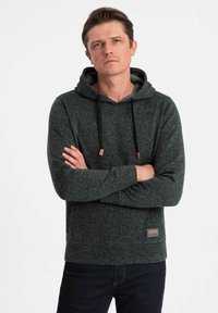 Felpa con cappuccio verde scuro, caratterizzata da un motivo testurizzato, con cappuccio regolabile, tasca frontale e una patch logo nella parte inferiore.