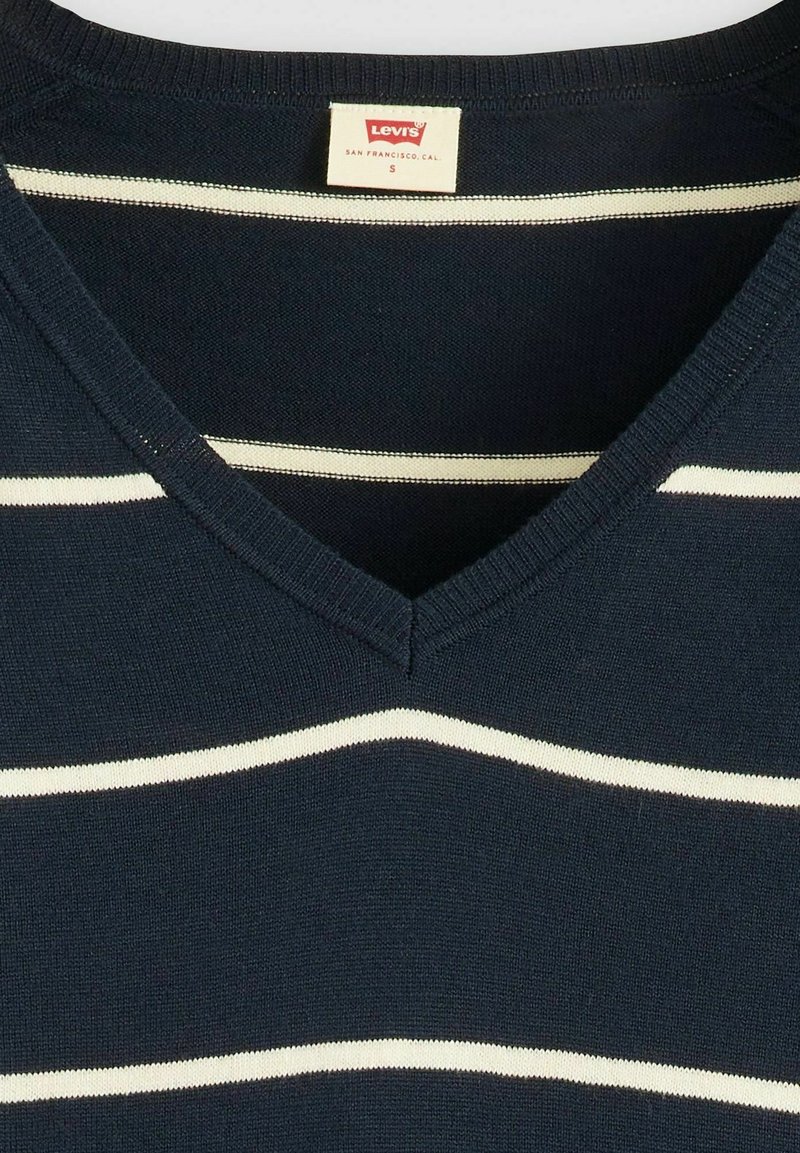 Pull en v marine à rayures horizontales blanches et crème, fabriqué en tissu tricoté, avec une étiquette « Levi's » dans la zone du cou.