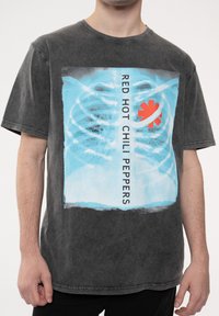 Gray oversized cotton t-shirt featuring a central graphic with blue x-ray design and "RED HOT CHILI PEPPERS" text, accented by a red logo.