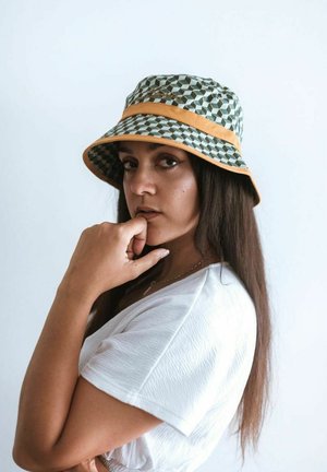 Cappello a secchiello con un motivo geometrico in verde e bianco, caratterizzato da una banda arancione. Il materiale sembra leggero e ha una superficie liscia.