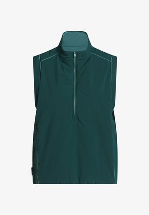 Prsluk bez rukava tamno zelene boje s visokim ovratnikom, prednjim dijelom na pola zatvarača i kontrastnim šavovima. Izrađen od laganog, glatkog tkanja bez vidljivih kopči.