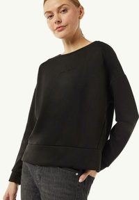 Czarny sweatshirt z okrągłym dekoltem, ściągaczami na mankietach i teksturowanym logo. Gładki materiał, luźny krój i prosty design bez ozdób.