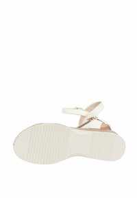 Sandali bianchi con suola texturizzata, dotati di cinturino alla caviglia e accenti in metallo dorato. Il design è open-toe con tacco piatto.
