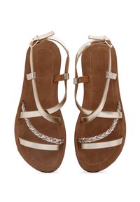 Sandali piatti color oro con molteplici cinturini sottili, caratterizzati da un dettaglio intrecciato in marrone chiaro, bianco e marrone su una suola in camoscio marrone.