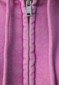Sudadera con capucha rosa con cremallera presenta una tela texturizada, bordes acanalados y una cremallera central con un tirador metálico.