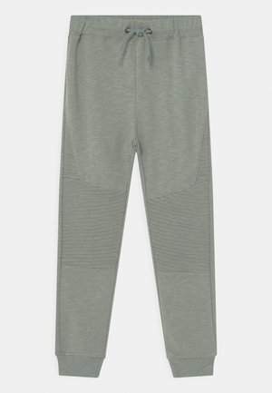 Vaaleanharmaat urheiluhousut, joissa on nyöritys vyötäröllä, sileä pinta, sivuilla resorikoristeet ja kapeutetut lahkeet nilkoissa.