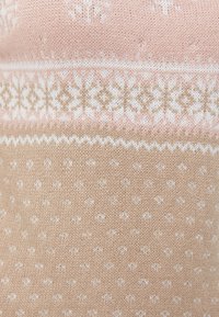 Tissu tricoté doux rose et beige avec motifs géométriques blancs et flocons de neige en bandes horizontales.