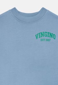 Svetlo modrý crewneck mikina s zeleným nápisom "VINGINO EST.1997" potlačeným na ľavej hornej časti hrude.