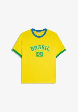 Gelbes T-Shirt mit blauem Kragen und grünen Ärmelsäumen, mit dem Schriftzug "BRASIL" und einer Grafik der brasilianischen Flagge in der Mitte.
