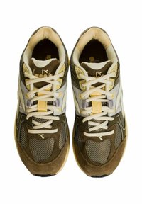 Scarpe da ginnastica marroni e beige realizzate con materiali in rete, suede e sintetici. Presentano lacci bianchi e dettagli riflettenti. Forma della punta arrotondata.