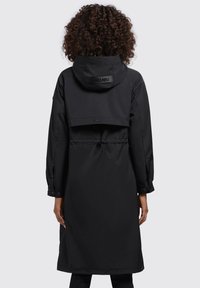 Cappotto impermeabile nero con cappuccio, vita regolabile con cordino e maniche lunghe. Tessuto liscio e resistente all'acqua con dettaglio superiore accorciato.