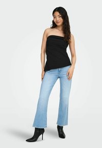 Must mustriba tops, mille sobiv mina, nagu ka helesinised flared teksad ja mustad kõrge kontsaga saapad. Sile, pehme kangast tekstuur.