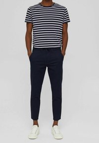 Pasywy, krótkie rękawy, koszulka w kolorze granatowym i białym, zestawiona z granatowymi, slim-fit spodniami, noszona z białymi sneakersami. Gładka tekstura bawełny.