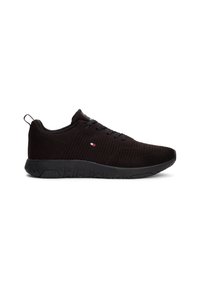 Baskets de sport basses noires avec tige en maille texturée, fermeture à lacets et petit logo drapeau rouge, blanc et bleu sur le côté, sur fond blanc.