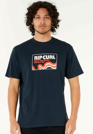 Navyblaue Baumwoll-T-Shirt mit einem bedruckten Rip Curl-Logo in retro Schriftart mit roten Akzenten. Kurze Ärmel, Rundhalsausschnitt. Normale Passform.