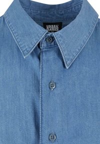 Denim srajca na gumbe s klasičnim ovratnikom, svetlo modre barve, z dvema sivo gumba na sprednji strani in zaključenim etiketom na vratu.