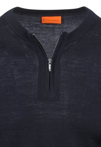 Marineblauwe pullover met een halve rits kraag, gemaakt van textuurstof. Heeft een subtiel patroon en een oranje merklabel bij de hals.